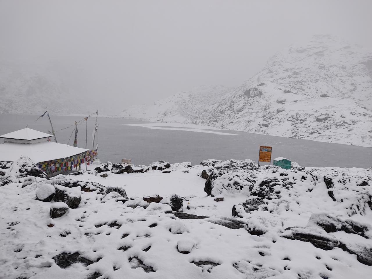 Gosaikunda lake covered in snow under grey sky